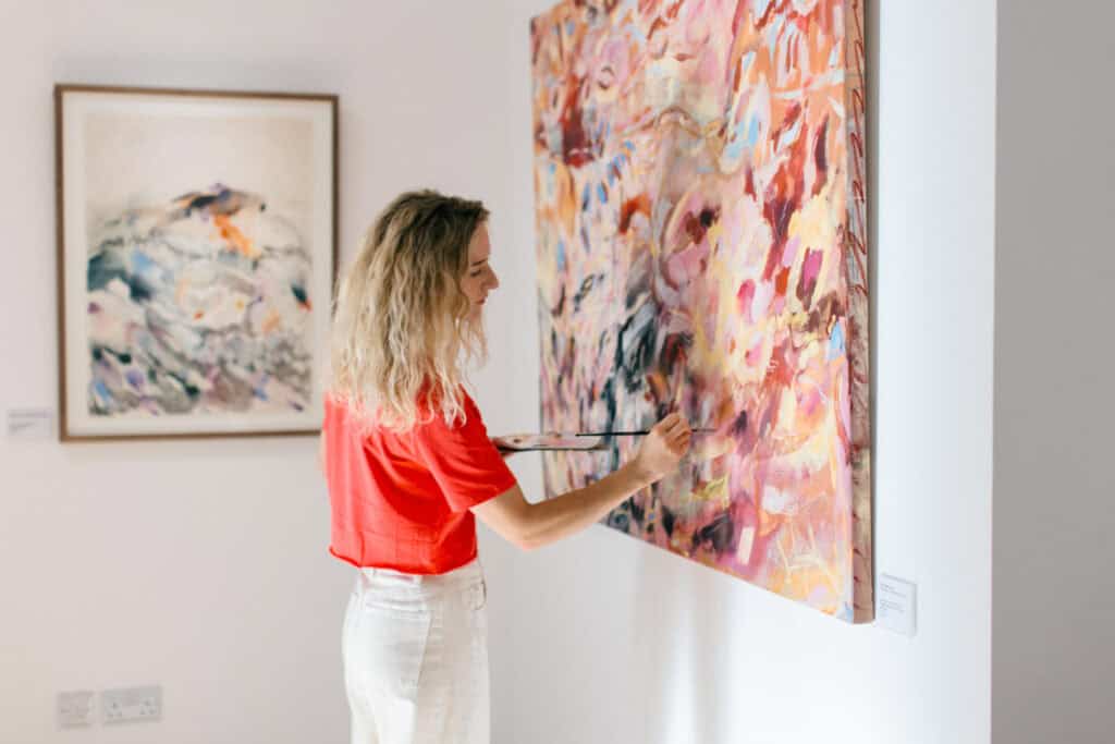 Abstract artist Emma Howell painting a large canvas on the wall in Sixteen Gallery in Cheltenham.