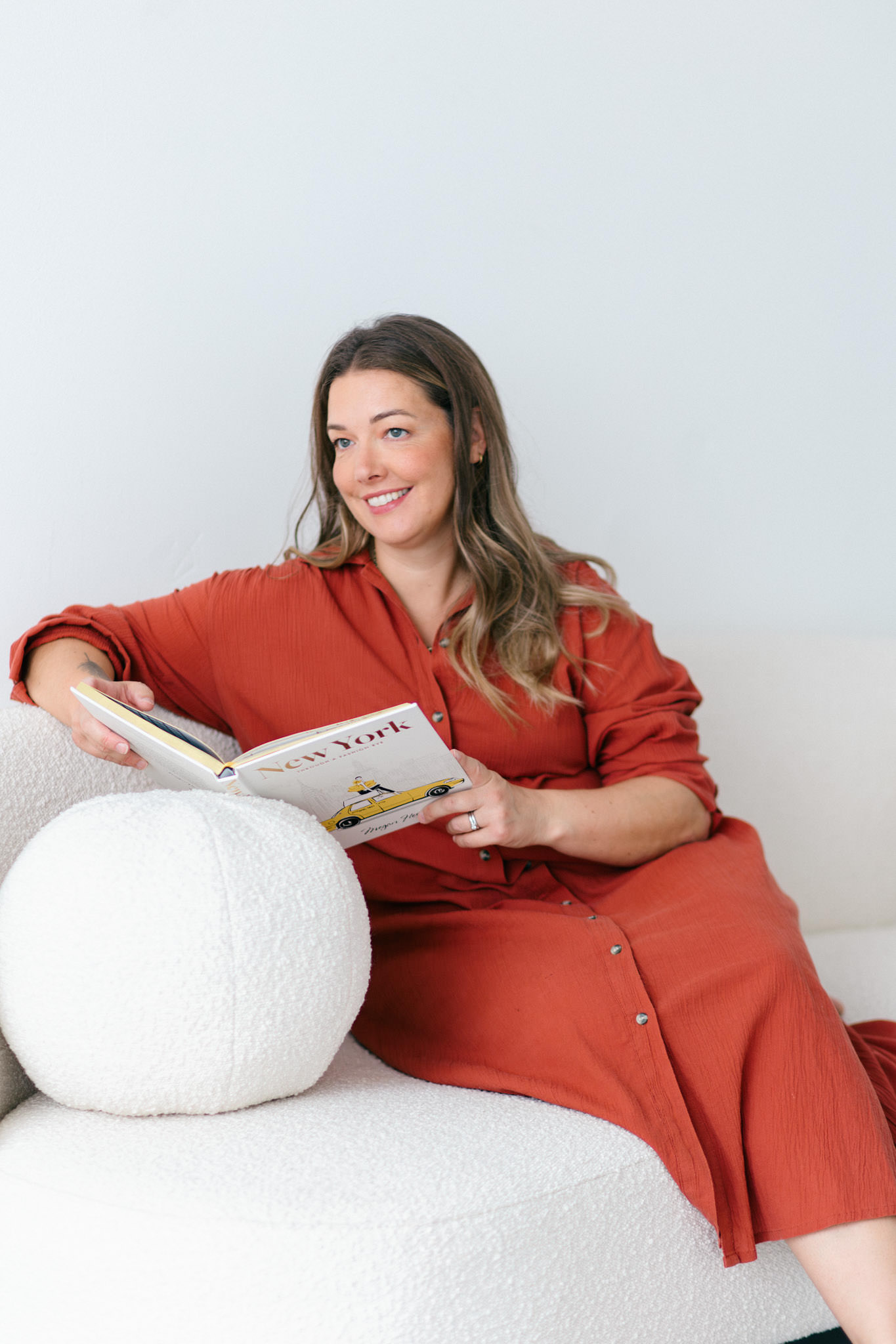 Cotswold make up artist Kerry Pargeter-Smith on a cream sofa in a rust coloured shirt dress.