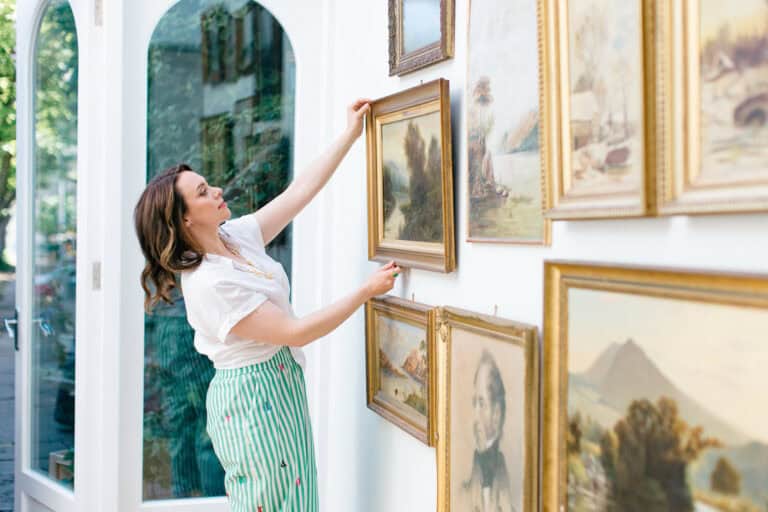 Abby Saks from Fox House Antiques in Woodstock, creating a gallery wall of antique paintings.