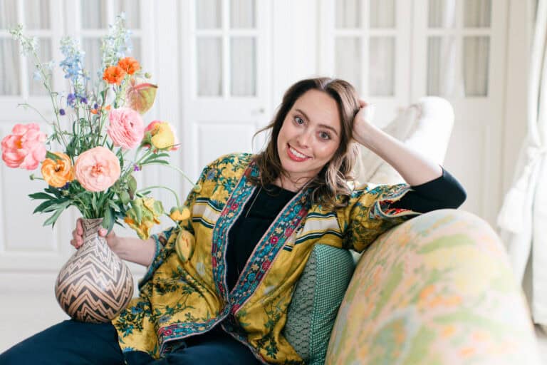 Antiques dealer Abby Saks from Fox House Antiques in Woodstock sitting on an antique yellow sofa smiling towards the camera